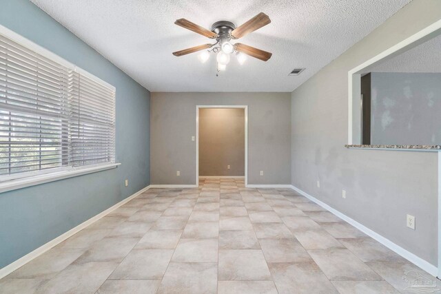 spare room with light tile patterned flooring, a textured ceiling, and ceiling fan