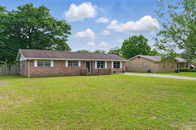 single story home featuring a front lawn, brick siding, fence, and driveway
