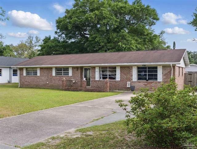 ranch-style house with brick siding, a front yard, roof with shingles, and concrete driveway