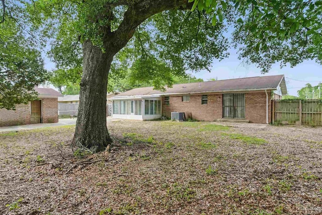 back of house with brick siding, central air condition unit, and fence
