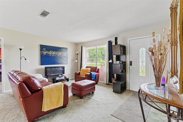 living area with light carpet, visible vents, and a textured ceiling