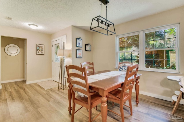 dining space with a textured ceiling and light hardwood / wood-style floors