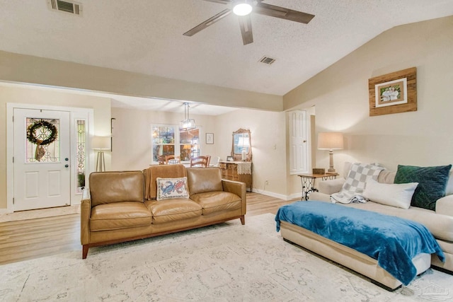 living room featuring a textured ceiling, light wood-type flooring, ceiling fan, and lofted ceiling