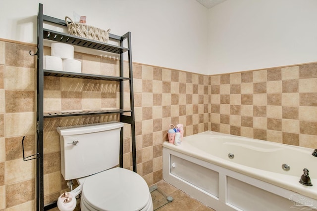 bathroom with tile patterned floors, a tub to relax in, toilet, and tile walls