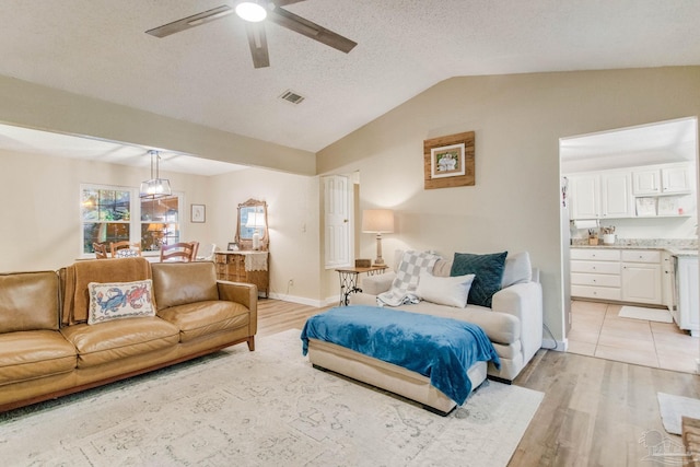 bedroom with vaulted ceiling, ceiling fan, light hardwood / wood-style flooring, and a textured ceiling