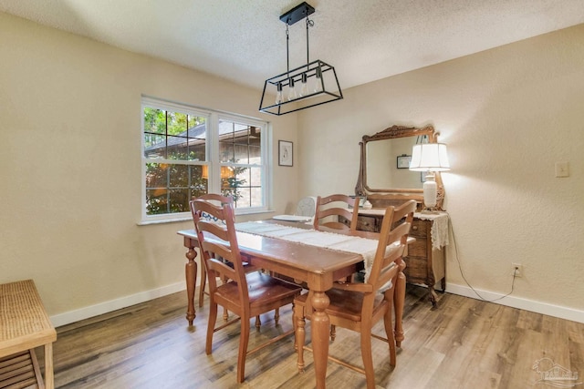 dining area with light hardwood / wood-style flooring and a textured ceiling