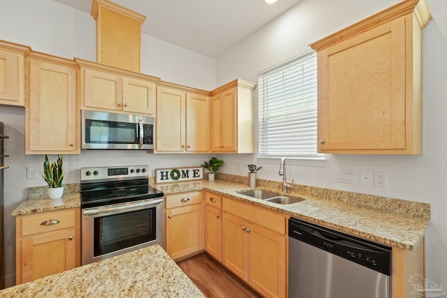kitchen featuring appliances with stainless steel finishes, a sink, and light brown cabinets