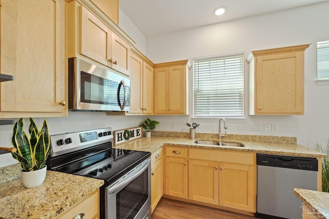 kitchen featuring stainless steel appliances, a sink, light brown cabinets, light stone countertops, and recessed lighting