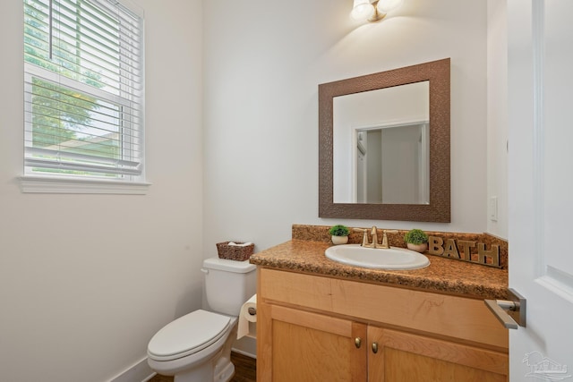 bathroom with toilet, vanity, and baseboards