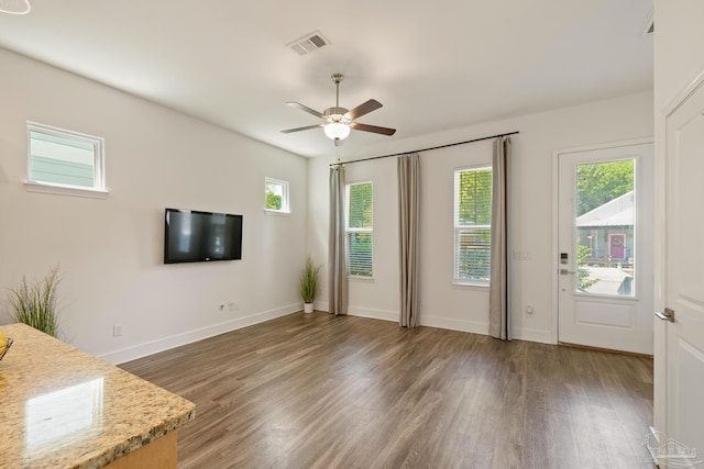 unfurnished living room featuring wood finished floors, a ceiling fan, and baseboards