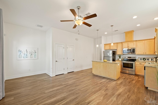 kitchen featuring stainless steel appliances, light brown cabinetry, a center island, light wood-style floors, and recessed lighting