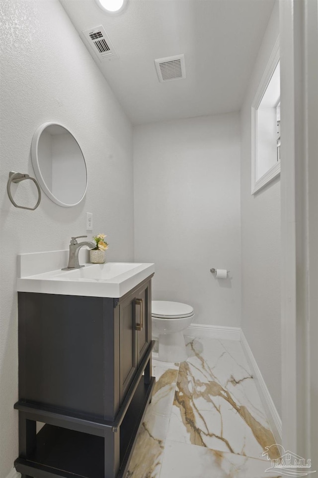 half bath with visible vents, marble finish floor, vanity, and toilet