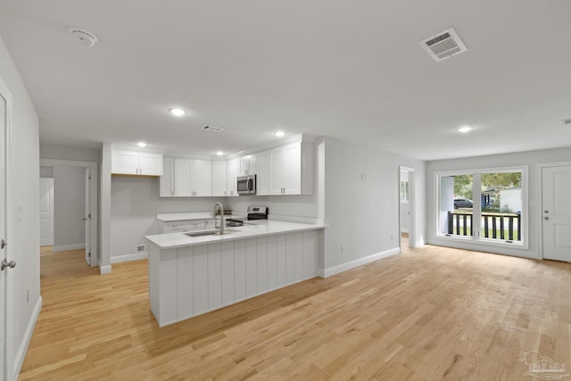 kitchen with visible vents, appliances with stainless steel finishes, a peninsula, and white cabinetry