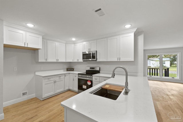 kitchen with visible vents, light countertops, white cabinets, stainless steel appliances, and a sink