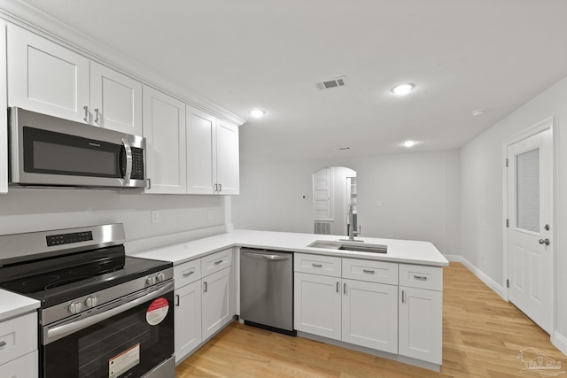 kitchen featuring visible vents, appliances with stainless steel finishes, a peninsula, arched walkways, and a sink