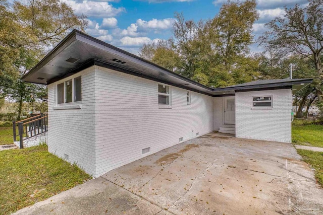 view of side of property with entry steps, a patio, brick siding, and crawl space