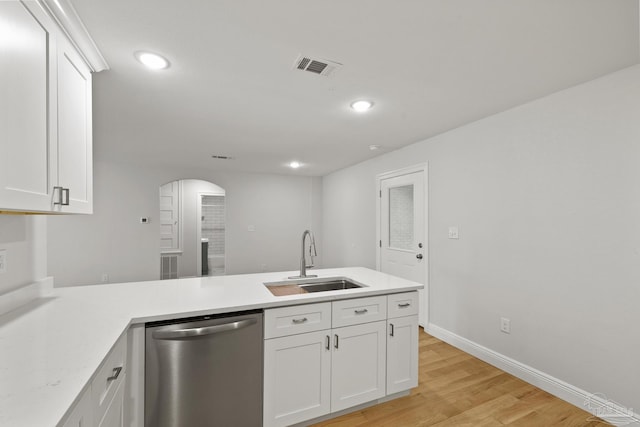 kitchen featuring visible vents, a sink, stainless steel dishwasher, arched walkways, and a peninsula