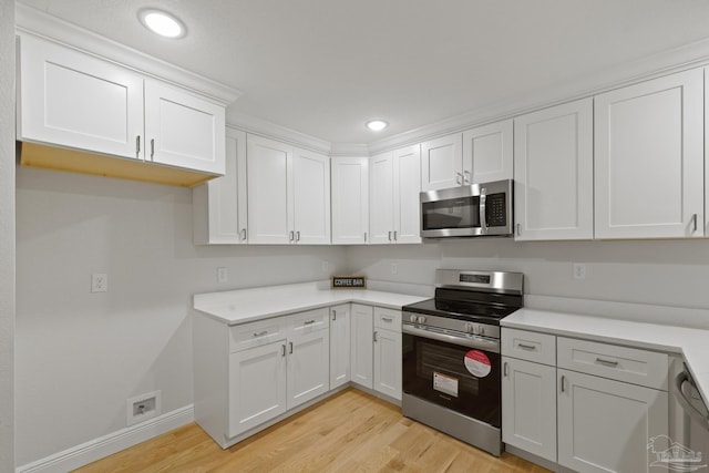 kitchen featuring light wood finished floors, appliances with stainless steel finishes, white cabinetry, and light countertops