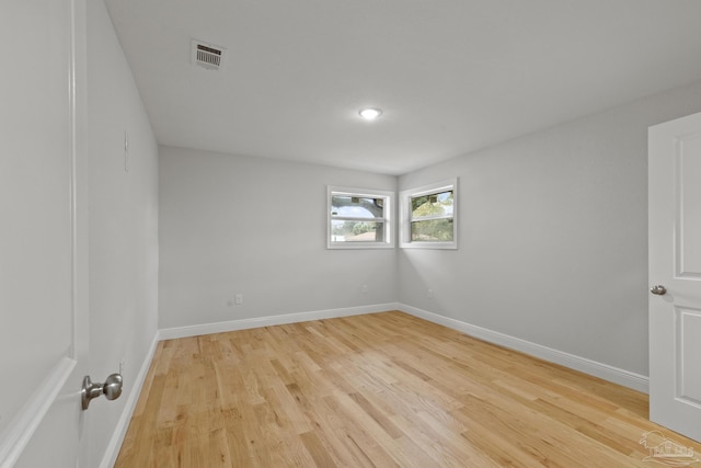 spare room with light wood finished floors, visible vents, and baseboards