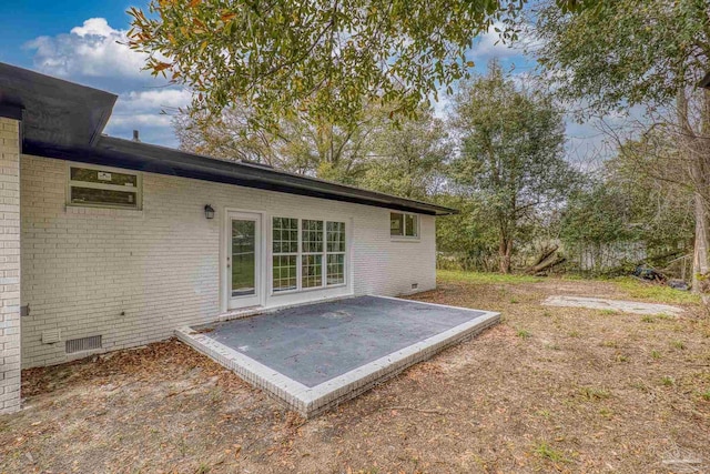 exterior space with crawl space, brick siding, and a patio area