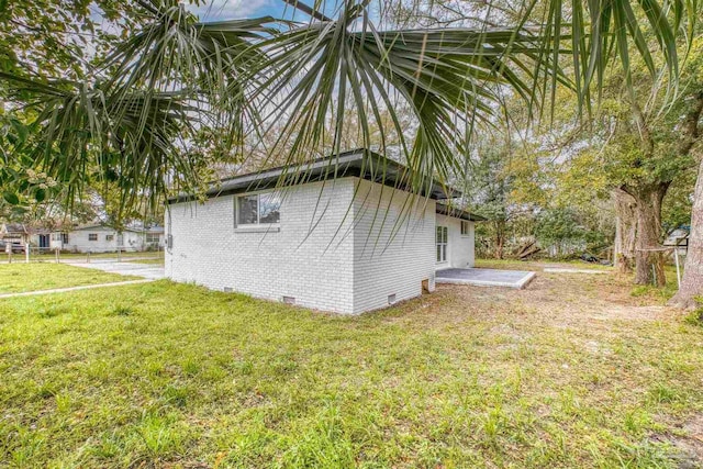 view of side of property featuring a lawn, brick siding, and crawl space