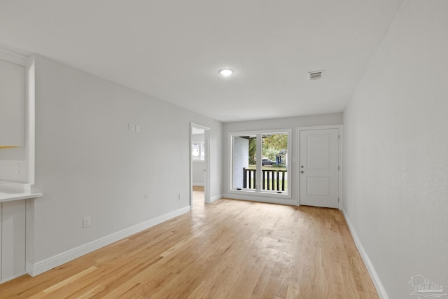 empty room featuring baseboards, visible vents, and light wood finished floors