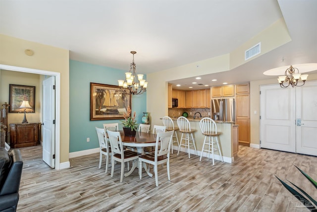 dining area with a chandelier, sink, and light hardwood / wood-style flooring