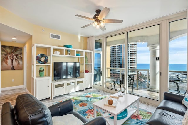 living room featuring expansive windows, ceiling fan, and light hardwood / wood-style flooring