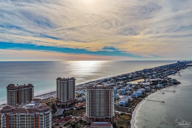 aerial view at dusk featuring a view of the beach and a water view