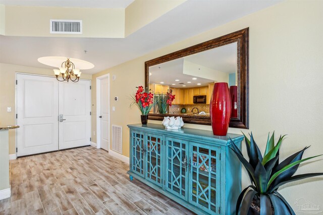 entryway featuring an inviting chandelier and light wood-type flooring