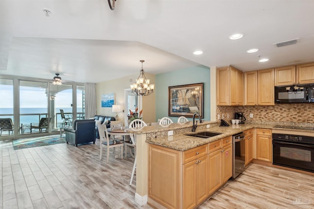 kitchen featuring sink, a water view, tasteful backsplash, kitchen peninsula, and black appliances