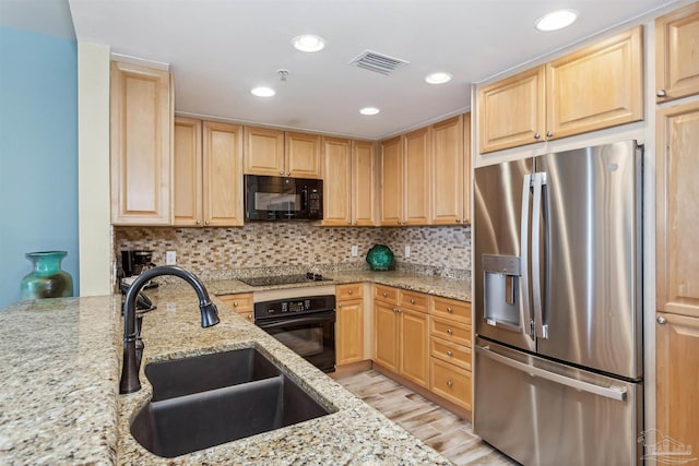 kitchen featuring sink, backsplash, light stone counters, black appliances, and light brown cabinets