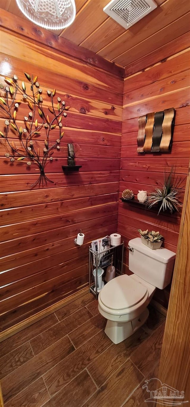 bathroom featuring wooden ceiling, wooden walls, and toilet