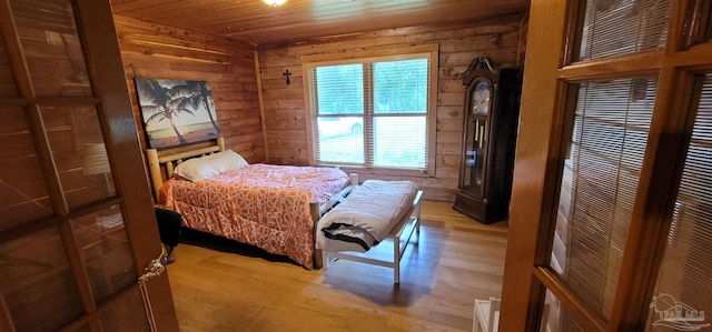 bedroom featuring light hardwood / wood-style floors, wooden ceiling, and wooden walls