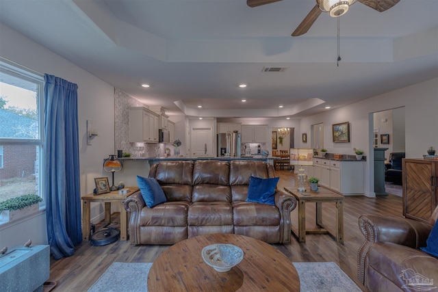 living area featuring ceiling fan, a raised ceiling, recessed lighting, wood finished floors, and visible vents