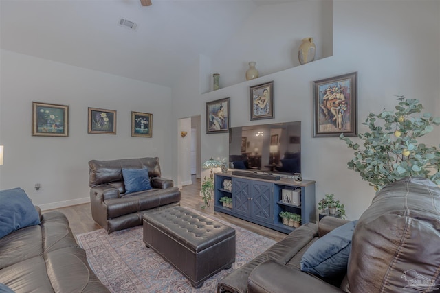 living area featuring baseboards, high vaulted ceiling, visible vents, and wood finished floors