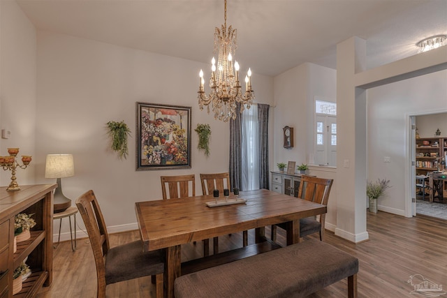 dining room featuring baseboards, light wood-type flooring, and a notable chandelier
