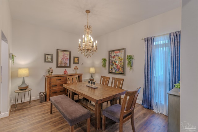 dining space featuring baseboards, a notable chandelier, and wood finished floors