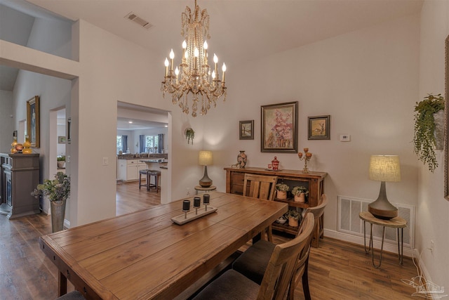 dining room with baseboards, visible vents, wood finished floors, and an inviting chandelier