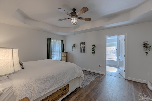 bedroom with baseboards, a tray ceiling, and multiple windows