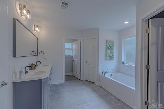 bathroom featuring a sink, double vanity, tile patterned floors, visible vents, and a bath