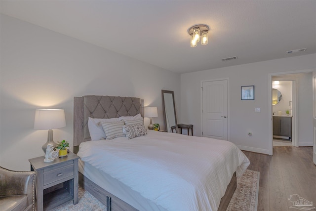 bedroom featuring baseboards, visible vents, and wood finished floors