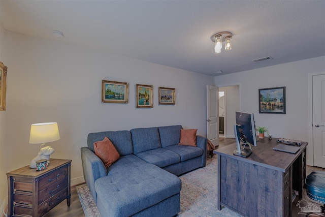living room featuring baseboards, light wood-style flooring, and visible vents