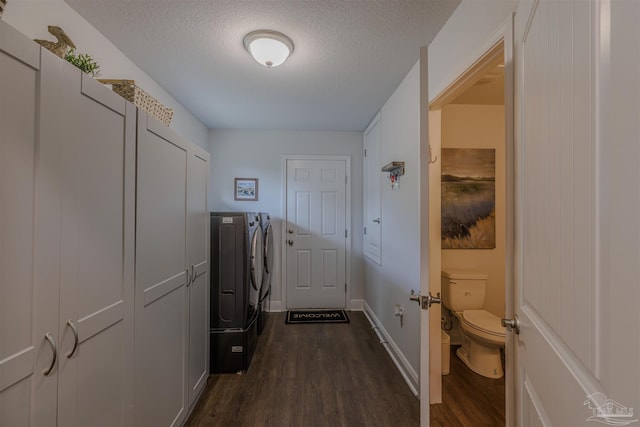 washroom featuring baseboards, washing machine and dryer, a textured ceiling, and dark wood-type flooring