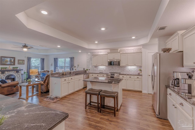 kitchen featuring a sink, stainless steel appliances, open floor plan, a tray ceiling, and visible vents