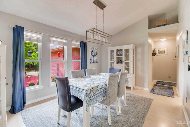905 Shadow Ridge Dr, Pensacola, FL 32514 - dining area featuring a chandelier, vaulted ceiling, light wood-style flooring, a textured ceiling, and baseboards