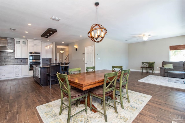 dining space with ceiling fan with notable chandelier and dark hardwood / wood-style flooring