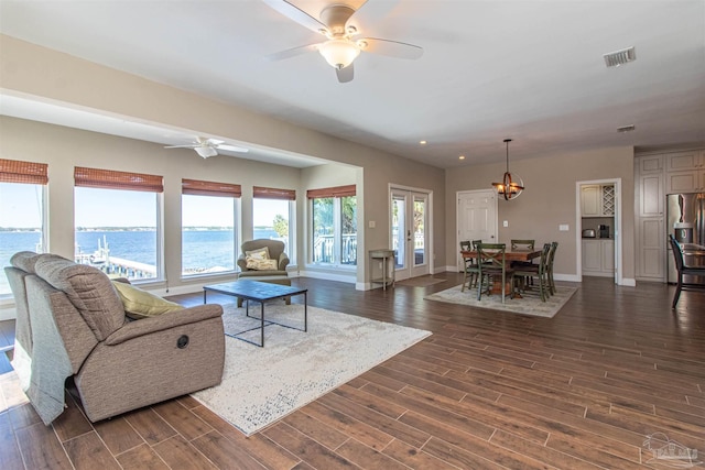 living room featuring a water view, ceiling fan with notable chandelier, french doors, and dark hardwood / wood-style floors