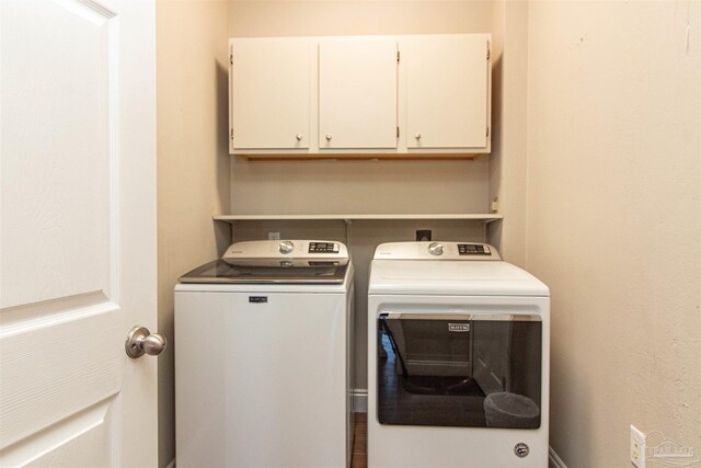 clothes washing area with washing machine and clothes dryer and cabinets