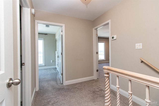 hall featuring carpet floors, visible vents, and baseboards